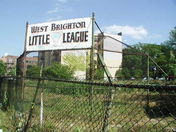 An overgrown field, with chain link fence, and a
sign indicating it used to be a Little League diamond.