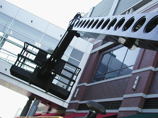 A shiny, black cherry picker, shown against an
enclosed glass pedestrian walkway.