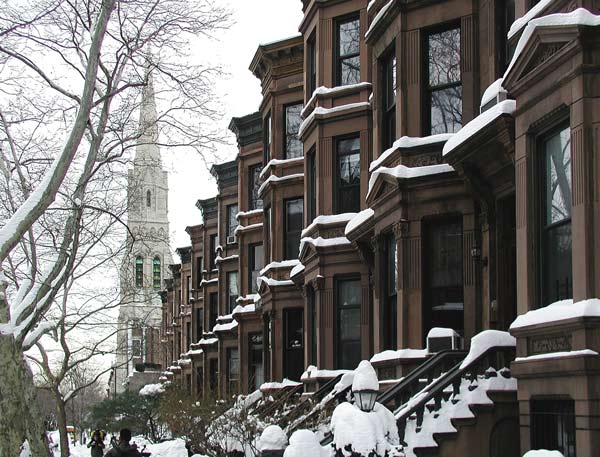 Brownstones and a steeple, covered in snow.