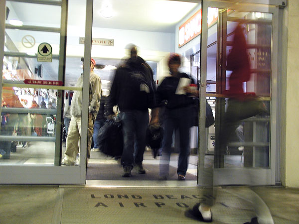 People move through aiport doors.