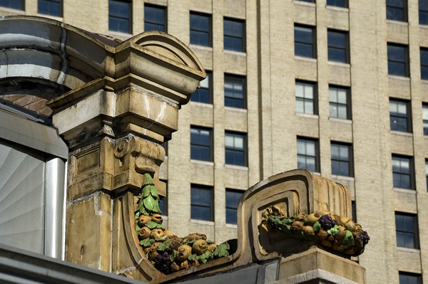 A
corner of the facade of an old subway entrance, with the
Williamsburg Bank Building in the background