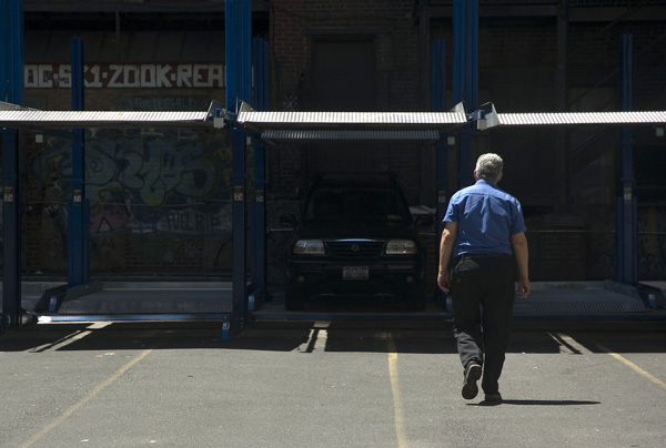 A parking lot attendant walks away from the camera, towards
the cars