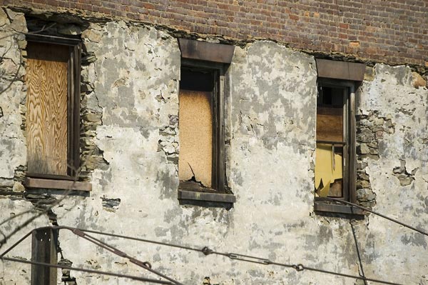 Three boarded-up windows in an abandoned building.