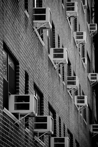 Rows of room unit air conditioners protrude from an
apartment building.