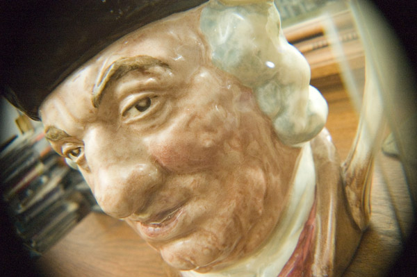 A Toby Mug of Samuel Johnson sits on a mantle, seen close
through a fish-eye lens.