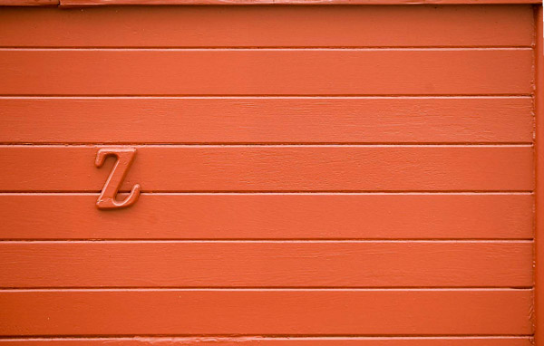 A red garage door with a wooden, red 'Z' on it.