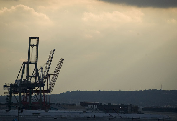 Loading cranes in silhouette against a grey, dusk sky.