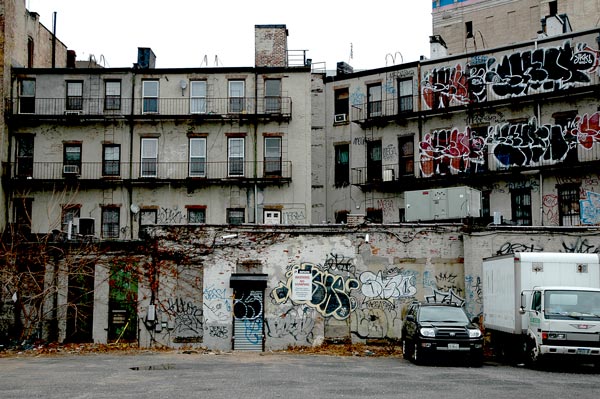 The back of an apartment building is covered in graffiti.