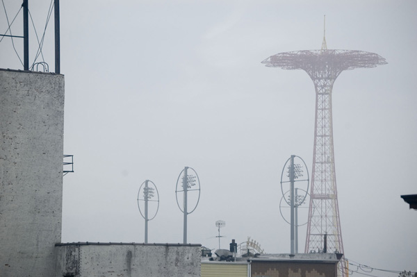 A tall red spindle-like ride stands alone in the fog.