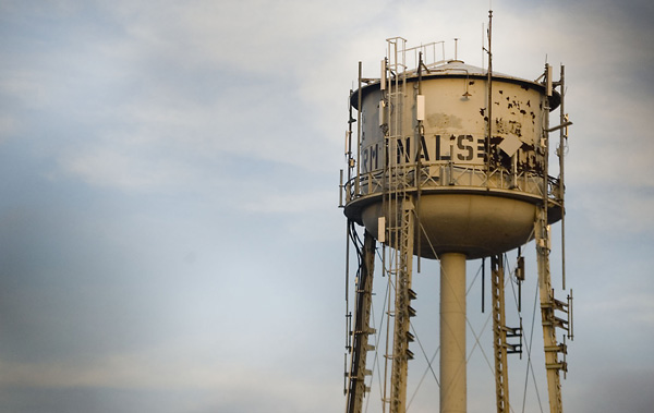 An old water tower with many ladders against a grey sky.