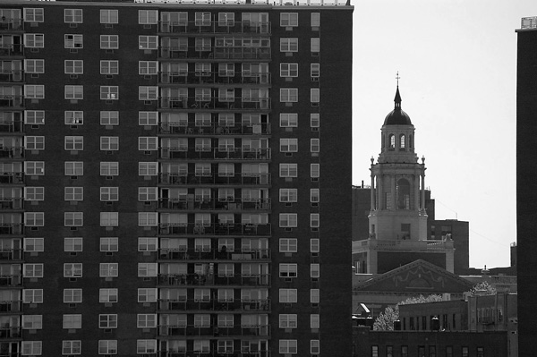 A building's cupola is framed by two tall apartment buildings.