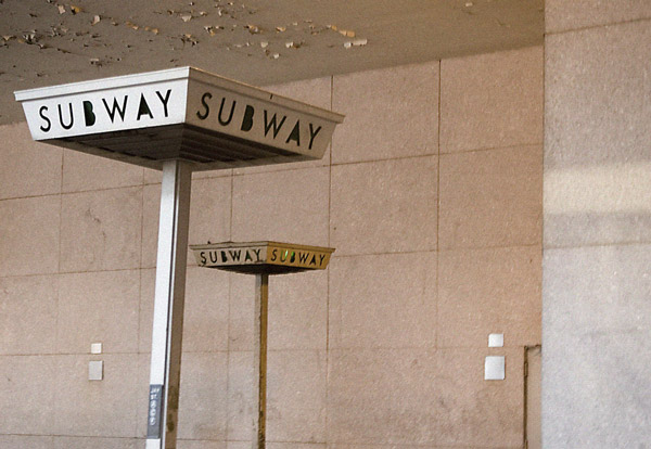 Two signs on poles, amid peeling paint, direct you to the
subway.