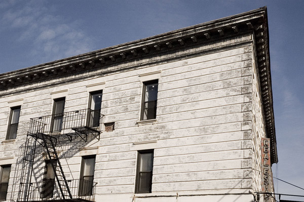 A white building with a fire escape shows signs of peeling
paint.