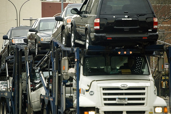 A trailer full of new cars and SUV's heads into the
foreground.