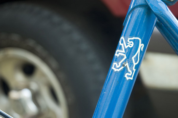A blue bike frame with the lion logo of Peugeot.