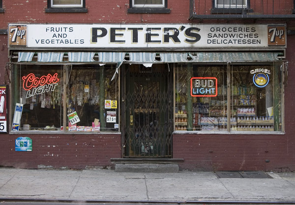 A convenience store at street level of a brick building,
with old signs.