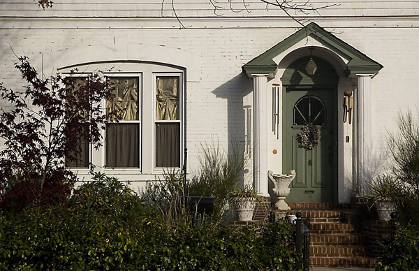 Harsh light hits a white-painted brick home with a
green awning over its entrance.