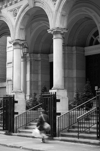 A person walks by the stairs and high arches of a
church entrance.