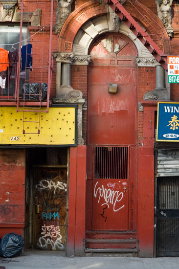 A red door, on an old red building, surrounded by
colorful signs.