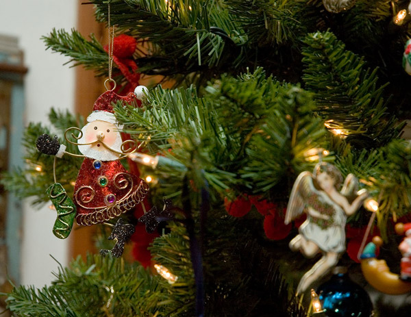 A metallic, shimmering Santa dangles in a Christmas
tree.