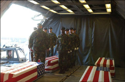 Flag draped coffins of soldiers killed in Iraq are being
received on aircraft, while soldiers stand at attention.