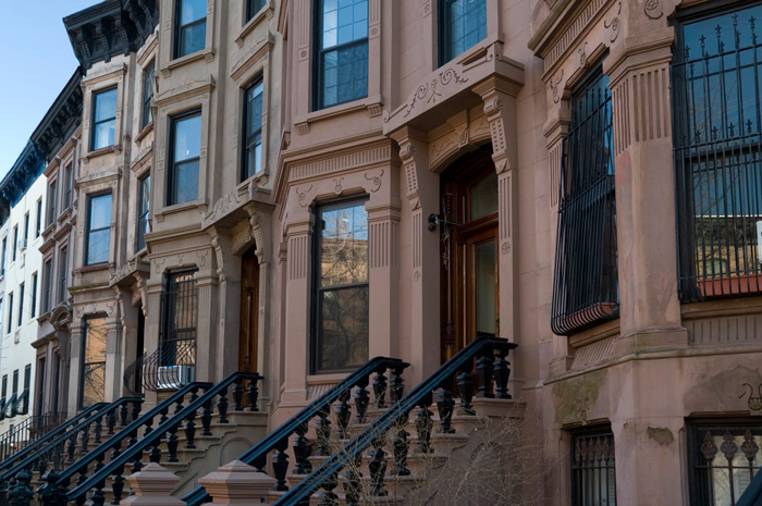A series of 19th Century brownstones have engraved details around their doors and windows.