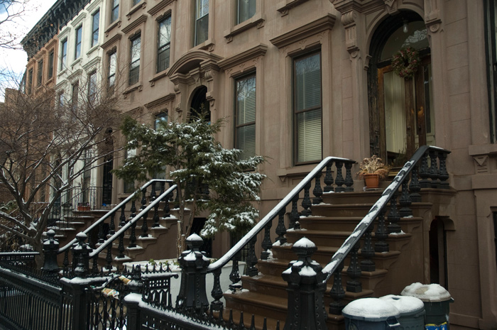 The staircases leading up to a row of brownstones have been highlighted by a small layer of snow.