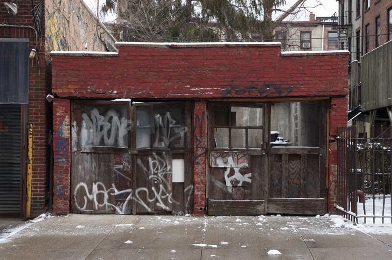 A brick two car garage, with graffiti.