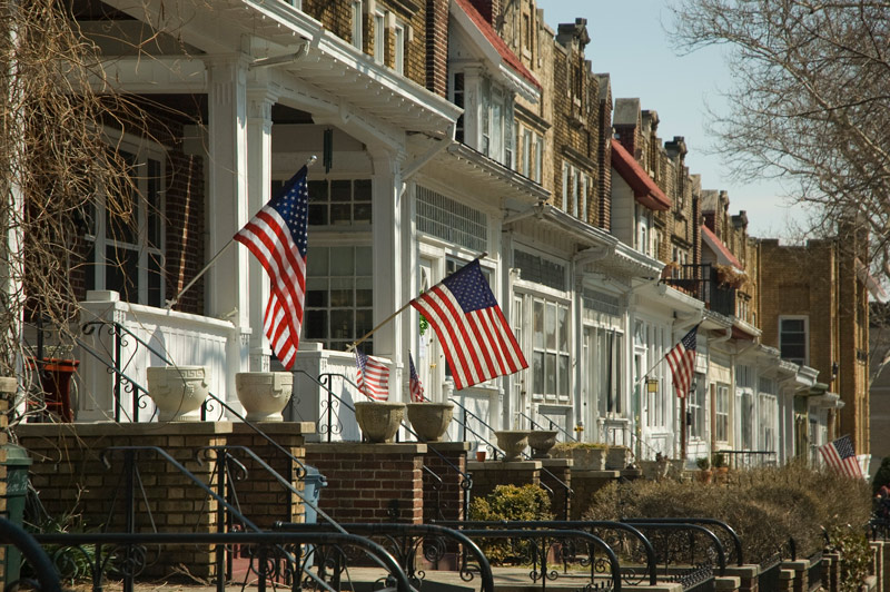 The photo shows a row of houses, many with American flags hanging in front.