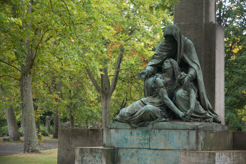 The photo shows a sculpture at a grave of a grieving woman and a figure of death.